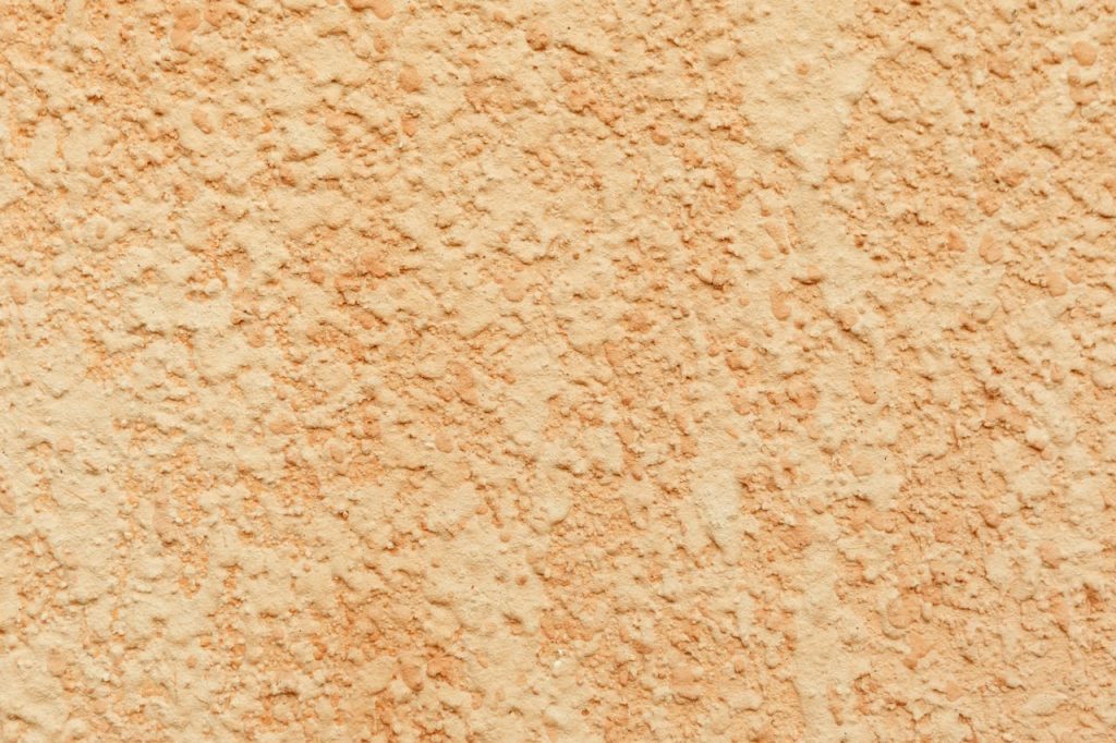 Close-up of a textured stucco wall with a rough plaster finish, ideal for backgrounds.