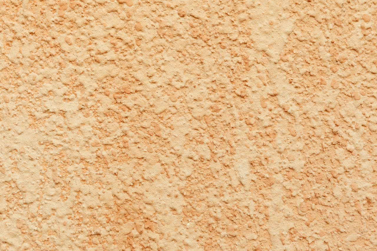 Close-up of a textured stucco wall with a rough plaster finish, ideal for backgrounds.