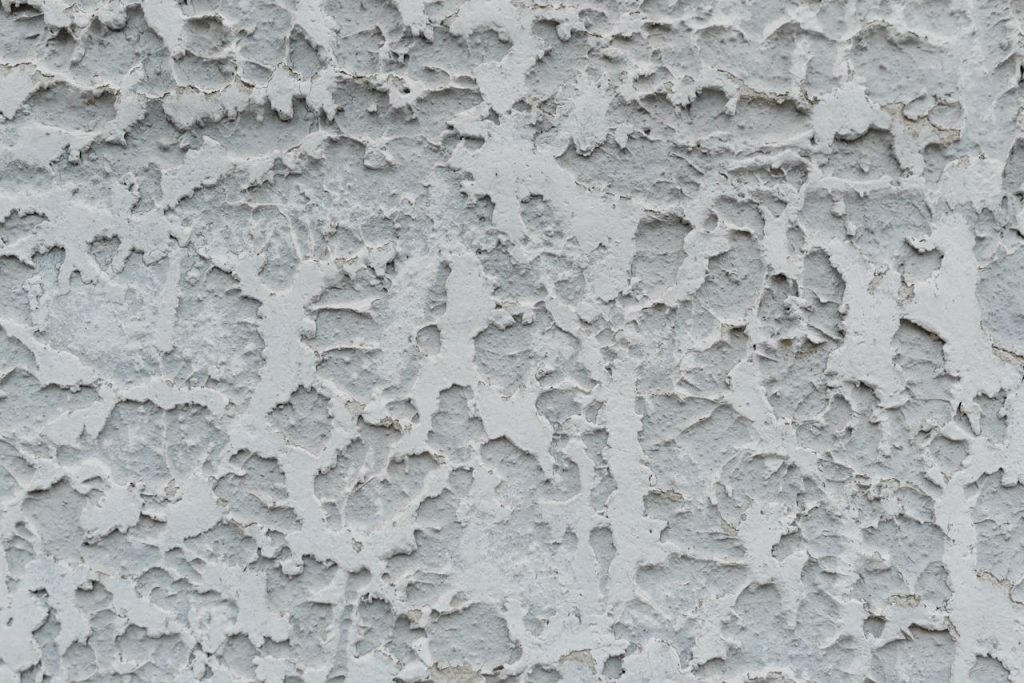 Close-up of a textured stucco wall with weathered, rough patterns and grunge look.